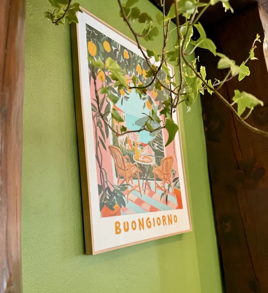 Gerahmtes Buongiorno-Poster an olivgrüner Wand, davor Efeuranken