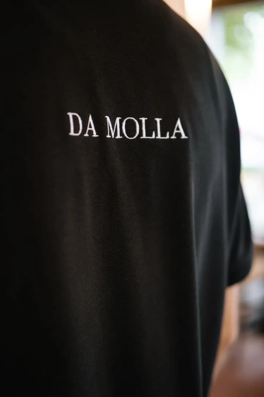 Schwarzes Poloshirt mit Da-Molla-Stickerei auf dem Rücken