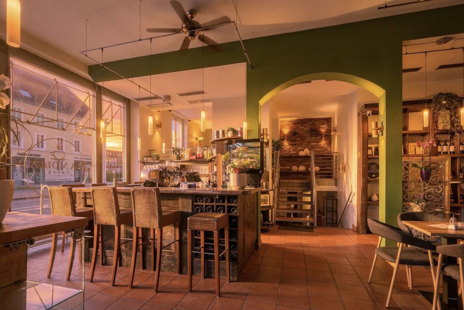 Innenraum des Da Molla Caffè: Bar mit Siebträgermaschine, olivgrüne Wand und Terrakottaboden im Abendlicht