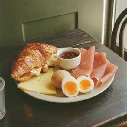 Frühstücksteller mit Croissant, Käse, Schinken und Eiern